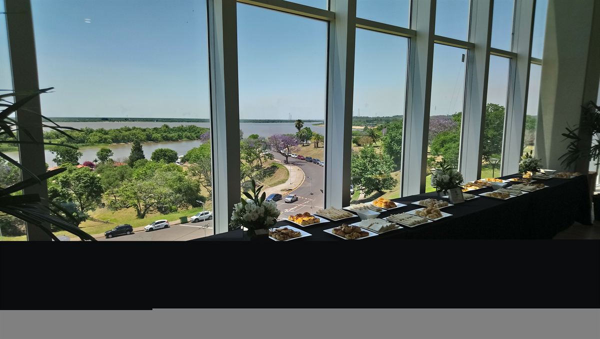 Mesa larga de coffee break frente a un ventanal con vista al río