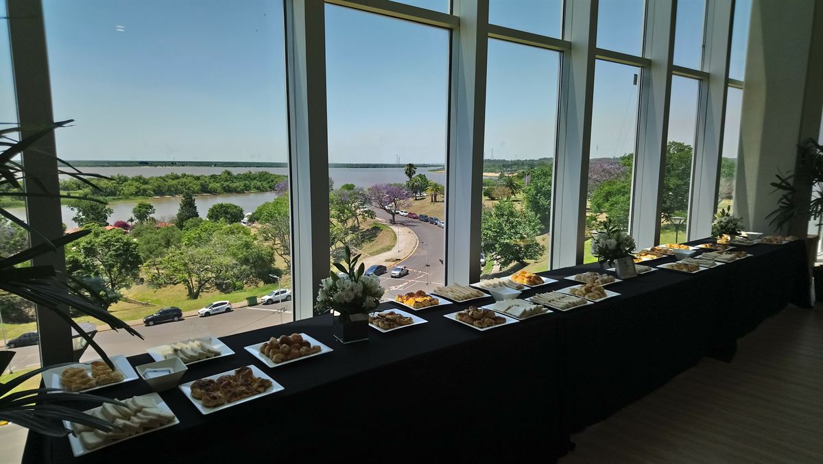 Salón de eventos con mesas de coffee break montadas en fila
